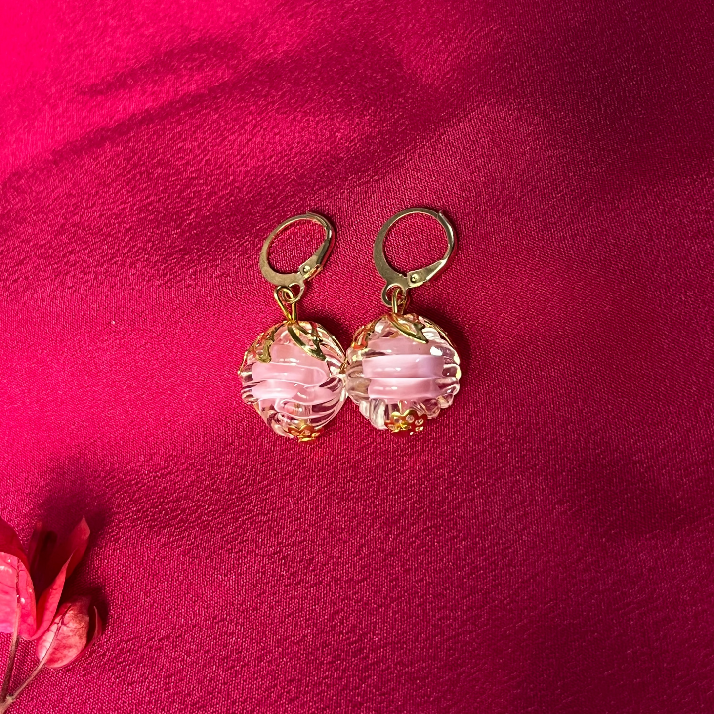Pink beaded earrings on a red fabric background