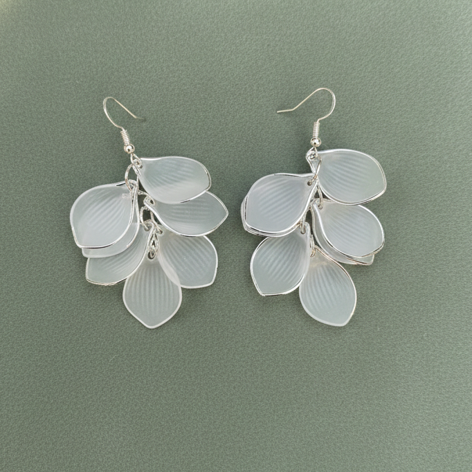 Silver leaf-shaped earrings on a green background