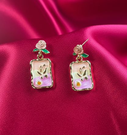 Pair of earrings with floral design on a pink satin background