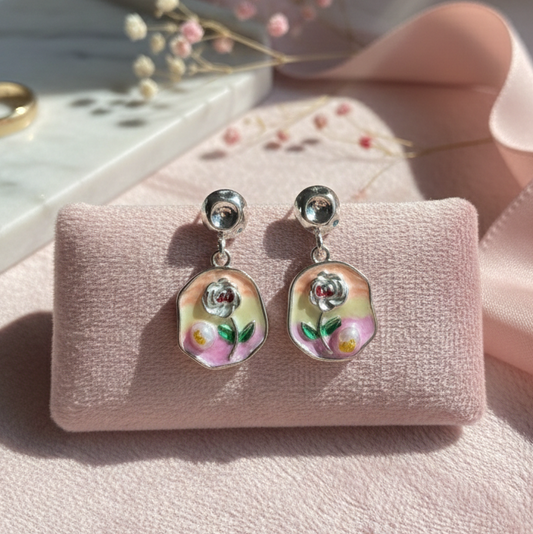 Pair of earrings on a pink jewelry display with a blurred background