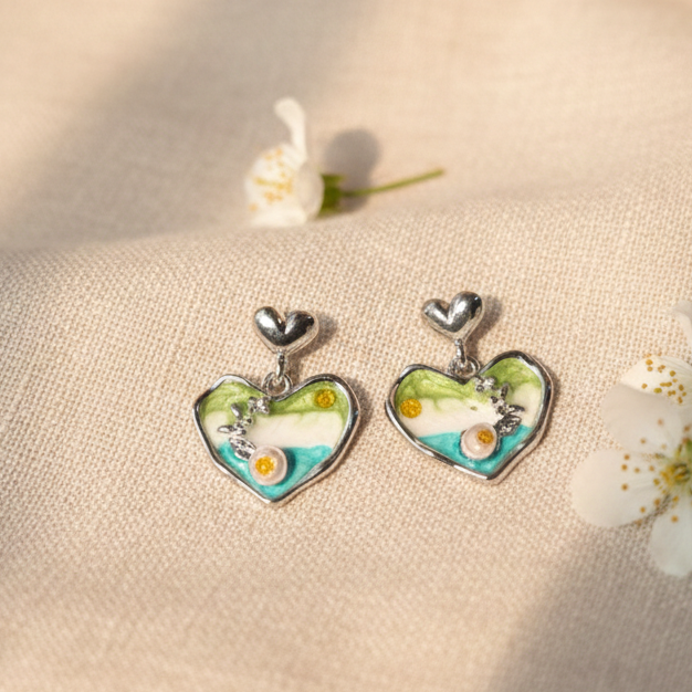 Heart-shaped earrings with floral design on a beige fabric background with flowers.