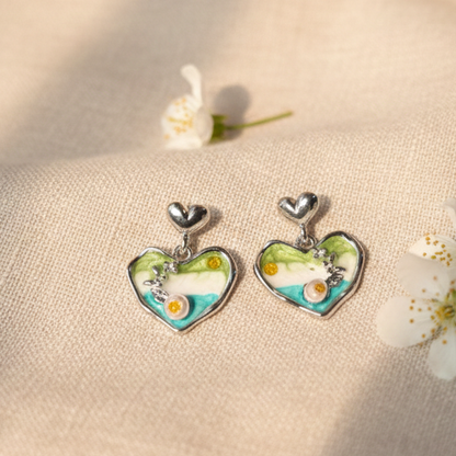 Heart-shaped earrings with floral design on a beige fabric background with flowers.