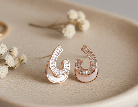 Rose gold earrings on a beige dish with small flowers