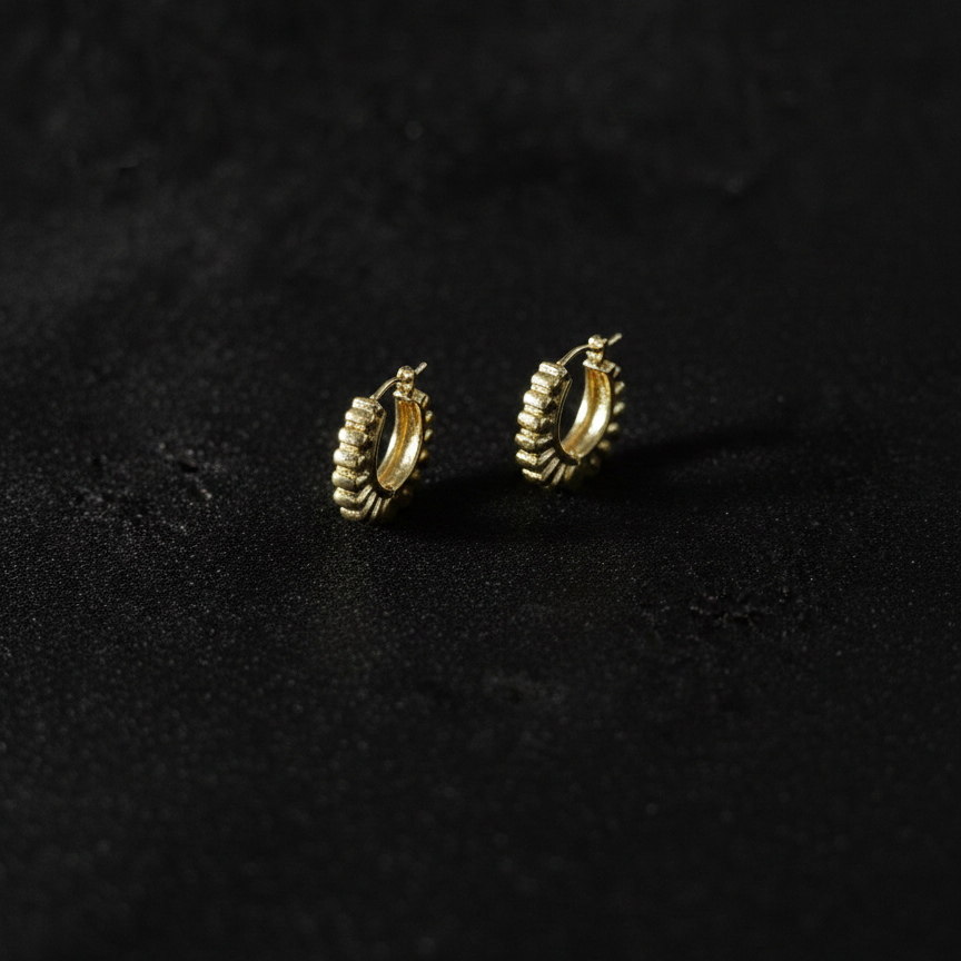 Gold hoop earrings on a dark textured surface