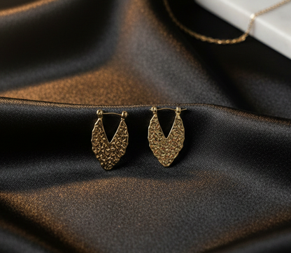 Pair of gold earrings on a dark fabric surface